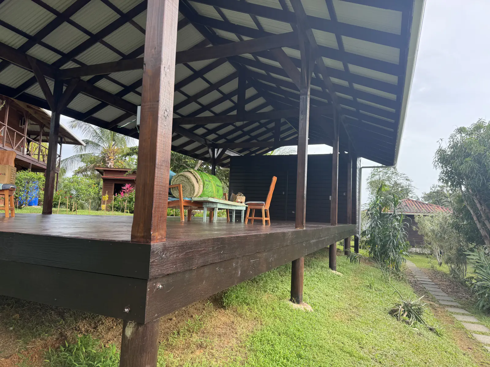 The pavilion deck in the morning with the main house beyond, chairs set out on the lawn side